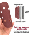 Holding a 5-inch sanding disc from 165 Piece 5 Inch Sanding Discs Set for Random Orbital Sander With Hook and Loop Backing