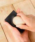 Sanding sponge block, black, held in hands for wood finishing