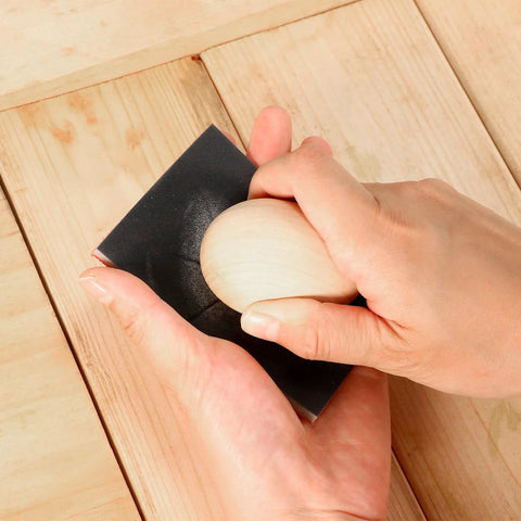 Sanding sponge block, black, held in hands for wood finishing