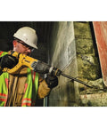 Person using lightweight corded SDS rotary hammer with Active Vibration Control to drill into masonry wall at work site