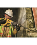 Worker using a lightweight corded SDS rotary hammer with Active Vibration Control to drill into concrete wall, showcasing 3.0 J impact energy.