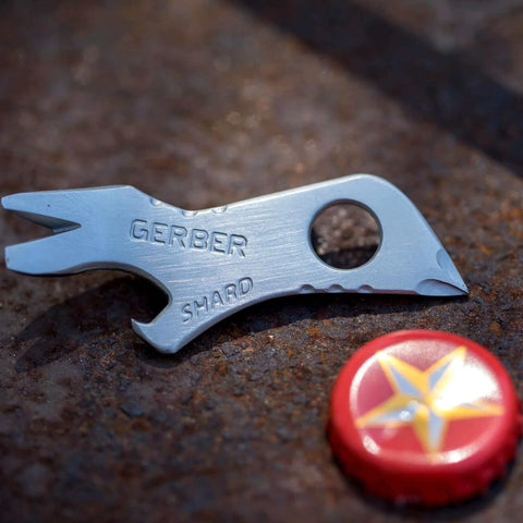 Shard 7 In 1 Keychain Multitool With Bottle Opener And Screwdriver, Lightweight Stainless Steel EDC Tool next to a bottle cap