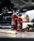 Shift Restore Automatic Transmission Additive 16 Oz Bottle for smoother shifts on a garage workbench with tools and cars