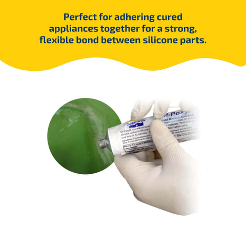 One Component Silicone Rubber Adhesive For Bonding RTV Silicone To Silicone And A Wide Range Of Substrates Including Urethane Plastics Ceramics Fabrics And More In A 3 Ounce Tube Delivers A Strong Flexible Bond That Sticks Like Crazy For Reliable Repairs being applied to a green surface by a gloved hand.