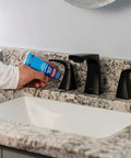 Applying Clear Silicone Sealant All-Purpose Waterproof Adhesive 2.7 Fl Oz Tube around a bathroom sink faucet on a granite countertop.