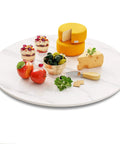 23.6 inch sintered stone lazy susan turntable in white with cheese, fruits, and desserts for tabletop serving.