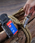 Close-up of SK5 Steel Utility Knife Blades 100 Pack with Dispenser next to utility knife cutting thick rope on wood surface