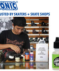 Man using Ultra Slick Sonic Super Oil Skate Bearing Lubricant for inline skate maintenance in shop, synthetic formula bottle shown.
