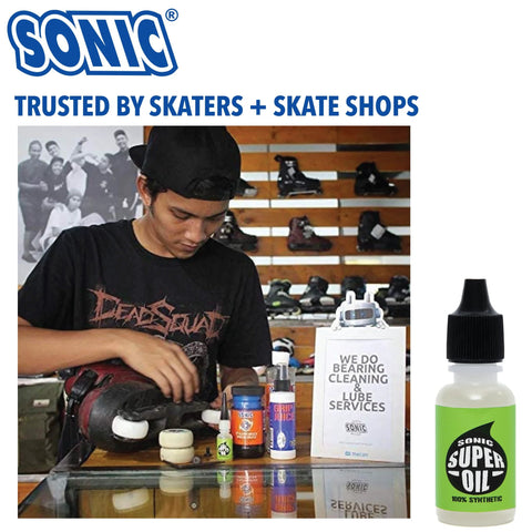 Man using Ultra Slick Sonic Super Oil Skate Bearing Lubricant for inline skate maintenance in shop, synthetic formula bottle shown.
