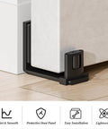 Sliding barn door bottom floor guide with adjustable U shape, black flush wall mounted design, shown installed under a door.