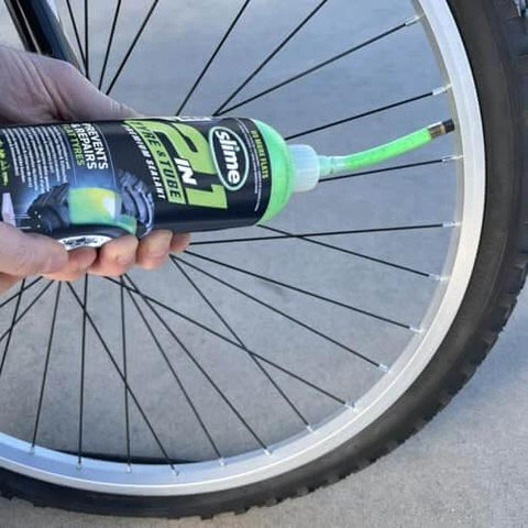Slime 10193 Tire and Tube Sealant Puncture Repair Sealant, 2-in-1, 16oz bottle being applied to a bicycle tire