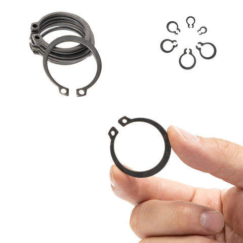 Close-up of hand holding Ultimate Snap Ring Shop Assortment Kit retaining ring, with scattered rings in background, Neiko 50458A