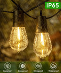 Close-up of Solar Outdoor String Lights 50 Feet Waterproof LED Edison S14 Bulbs in rain hanging outdoors.