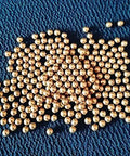 100pcs 1.8mm solid brass balls for electric switches machine precise copper ball scattered on a textured blue surface