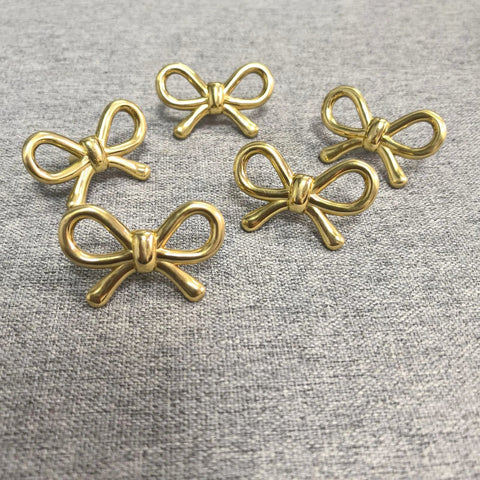 2 Pack Solid Brass Bow Drawer Knobs In Gold displayed on grey surface, showing elegant vintage cabinet hardware design.