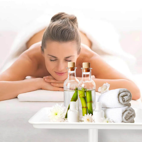 A woman receiving a spa massage with essential oils and towels on a tray; relaxation and rejuvenation scene.