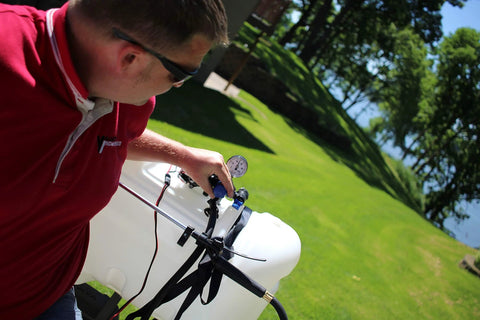 Person adjusting Universal Broadcast Sprayer Pressure Regulator with Quick Connect Bypass Port installed on a lawn sprayer tank