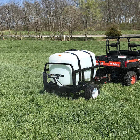 Tractor pulling a trailer with an Everflo 12V On-Demand Diaphragm Sprayer Pump - 5.5GPM, 60 PSI, Quick Attach Ports in a field.