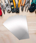 12 Piece Stainless Steel Shim Stock Kit 2.5 x 6 Inch For Leveling And Spacing next to various tools on a wooden surface