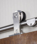 Close-up of Seventy Eight And Three Quarters Inch Single Roller Round Rod Barn Door Hardware Kit in champagne brass finish with wooden door.