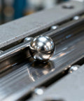 Close-up of stainless steel bearing ball on machine rail, from Stainless Steel Bearing Ball Set With 620 Pieces In 12 Sizes.