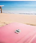 One marine-grade stainless steel folding D-ring tie-down anchor on pink beach surface