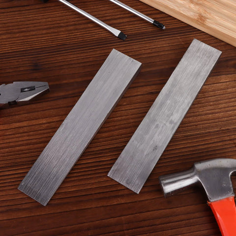 Two stainless steel wedges from Six Piece Stainless Steel Flange Wedge Set For Welding Lathe Machines 7x1.3in on a wooden surface.