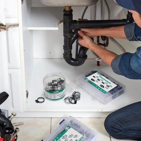 Man installing 175 Pcs Stainless Steel Hose Clamp Kit With Eight Sizes From One Quarter Inch To Two Inches under sink