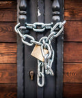 Close-up of a 304 stainless steel coil chain secured with a padlock on a wooden door for security.