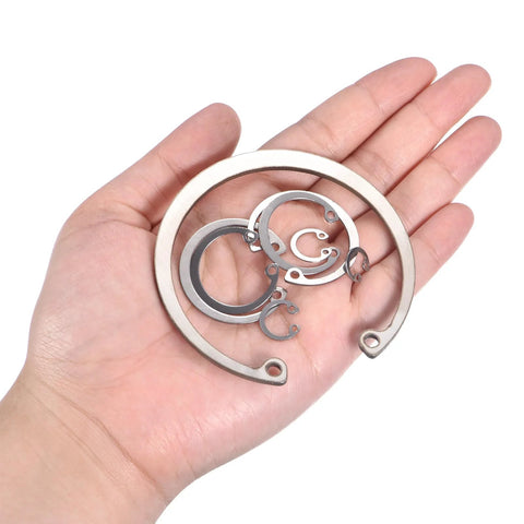 Stainless steel internal retaining rings (circlips) set in hand, varying sizes; includes a 72mm ring.