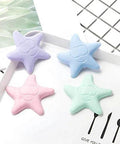 Four starfish-shaped bumpers in purple, blue, pink, and green, Self-Adhesive Silicone Door Handle Bumpers Protect Walls, Absorb Shocks, And Quiet Door Impacts With No Tools Required, Delivering Durable, Universal Wall Protection For Any Door, Knob, Or Handle Area, on a white surface.