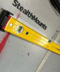Red Universal Level Holder 4 Pack With Locking Level Mounts holding a yellow level against a wall in a workshop.