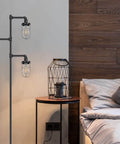 Three Head Steampunk Floor Lamp With Birdcage Shade Dope Industrial Rustic Edison Bulb Black Finish And Adjustable Cross Stand next to a bed