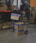 Person using a Steel Pneumatic Hand Truck Dolly - 600-Lb. Capacity, 10in. Tires, Powder-Coat Finish in a warehouse.