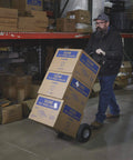 Person using Steel Pneumatic Hand Truck Dolly - 600-Lb. Capacity, 10in. Tires, Powder-Coat Finish to transport boxes in warehouse