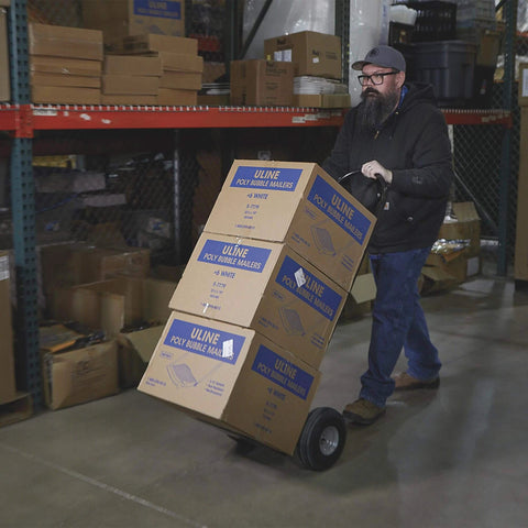 Person using Steel Pneumatic Hand Truck Dolly - 600-Lb. Capacity, 10in. Tires, Powder-Coat Finish to transport boxes in warehouse