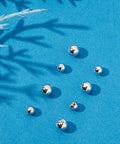 925 Sterling Silver Screw Ball Backings for Earrings, round 3-4mm, loose on blue background, hypoallergenic jewelry making supply.
