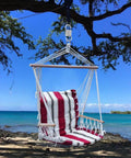 Striped hammock chair hanging from a tree with ocean and beach view in background