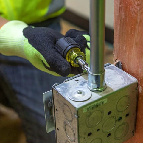 Person using 6-In-1 Stubby Screwdriver And Nut Driver with interchangeable shaft in electrical panel, showing compact design.