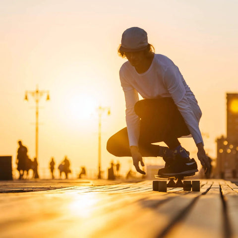 Skater in sunset using 54mm Skateboard Wheel Set with ABEC 9 Bearings Four Pack Cruiser Street Wheels on boardwalk.