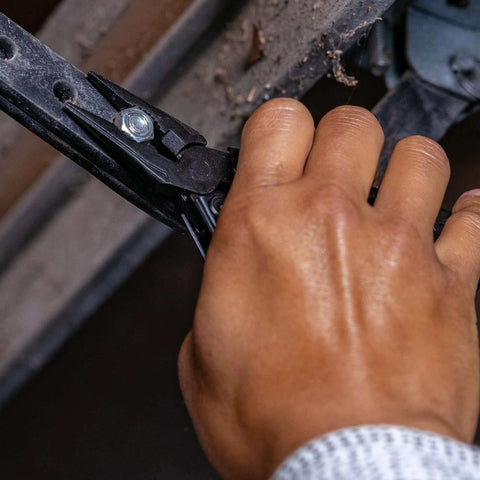 Hand using Suspension-NXT 15-In-1 EDC Multi Tool with needle nose pliers on metal structure
