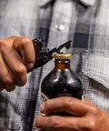 Person using Suspension-NXT 15-In-1 EDC Multi Tool With Pocket Knife to open a bottle, showcasing the bottle opener tool.
