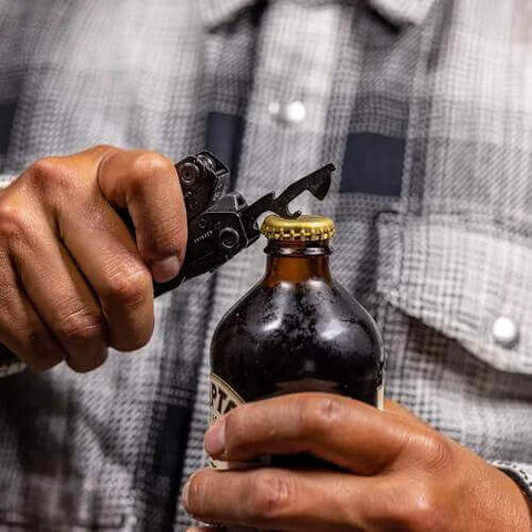 Person using Suspension-NXT 15-In-1 EDC Multi Tool With Pocket Knife to open a bottle, showcasing the bottle opener tool.