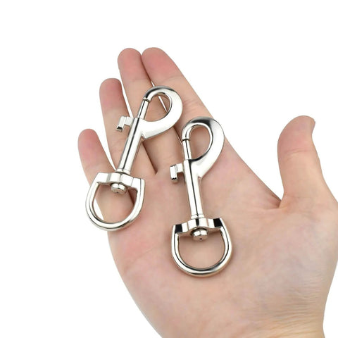 Person holding two Swivel Eye Bolt Snap Hooks For Pet Leash And Collar Heavy Duty Clips, zinc alloy construction, durable and smooth rotation.