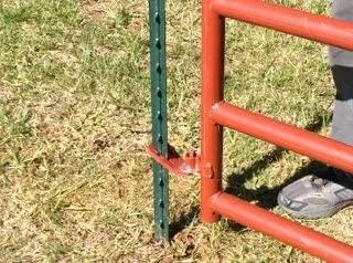 Patented T Post Hinge Pins for easy gate hanging from metal T posts, shown installed on a red gate with green T post outdoors.