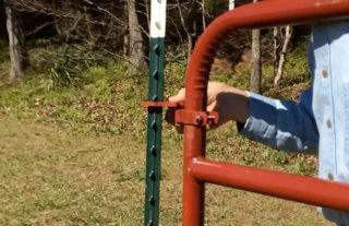 Person installing gate with Patented T Post Hinge Pins for easy gate hanging from metal T posts, showing secure connection.