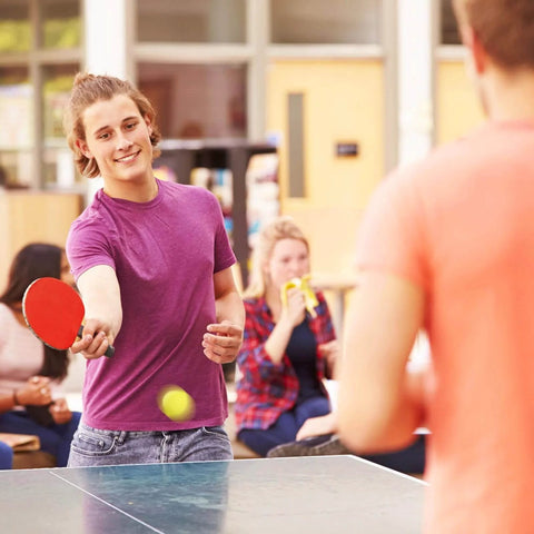 Person playing ping pong with colorful table tennis ball, highlighting use for 100 Pack Table Tennis Balls,40mm Colored Plastic Balls Beer Balls Bulk.
