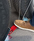 Using a foot to set the OneStep Wheel Chock Double Pack For Tandem Axle Trailers And RVs, 16 to 24 inch long, showing no kneeling setup.
