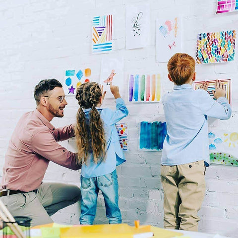 Teacher helping children hang art with Teacher Tape Pads Double Sided Removable Foam Tape For Wall Mounting 96 Pieces Per Pack