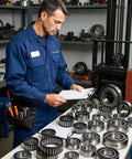 Technician inspecting industrial bearings, including forklift mast bearing 94447-01500 heavy duty replacement, in workshop setting.